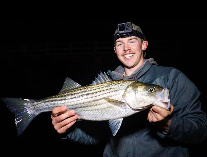 fishtalk reports editor Dillon holds up a striped bass